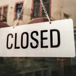 closed sign hanging on store front window